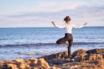 Young beautiful sportwoman practicing yoga. Coach teaching postures at the beach