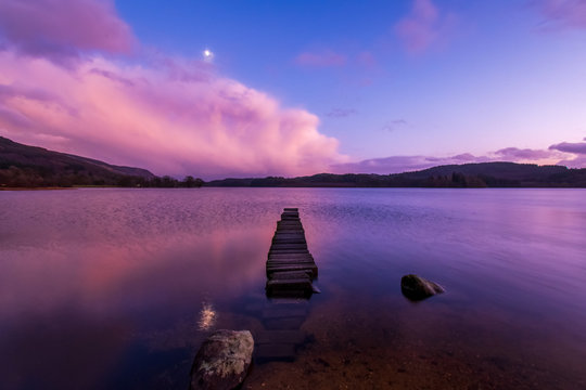 Sunset & moonrise over stone jetty in Loch Ard - Stirling, Scotland.