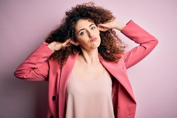 Young beautiful businesswoman with curly hair and piercing wearing elegant jacket Smiling pulling ears with fingers, funny gesture. Audition problem