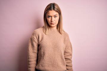 Fototapeta premium Young beautiful blonde woman wearing winter wool sweater over pink isolated background skeptic and nervous, frowning upset because of problem. Negative person.