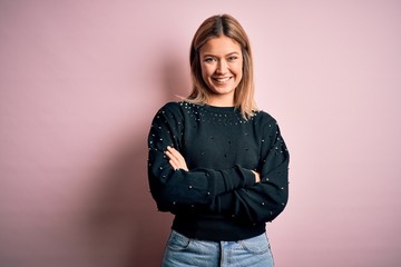 Young beautiful blonde woman wearing fashion sweater over pink isolated background happy face smiling with crossed arms looking at the camera. Positive person.