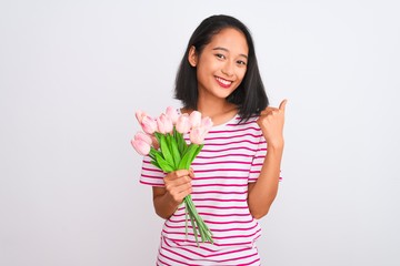 Young chinese woman holding bouquet of roses standing over isolated white background happy with big smile doing ok sign, thumb up with fingers, excellent sign