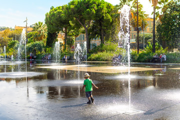A young boy with a hat plays and splashes in the Promenade du Paillon Park in the touristic old town area of Nice, France on the French Riviera. © Kirk Fisher