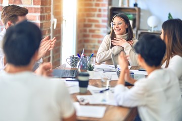 Group of business workers smiling happy and confident. Working together with smile on face applauding one of them at the office