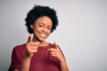 Fototapeta na wymiar Young beautiful African American afro woman with curly hair wearing casual t-shirt standing pointing fingers to camera with happy and funny face. Good energy and vibes.