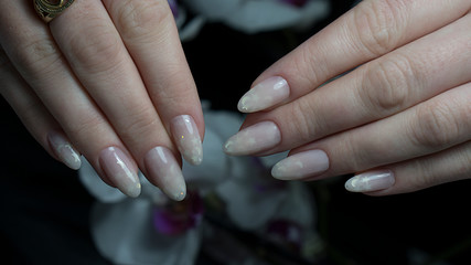 Beautiful female hands with nude manicure. Fingers with fresh pastel nude look manicure at short oval nails. Trend of natural beauty concept. 