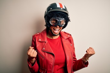 Young African American afro motorcyclist woman with curly hair wearing motorcycle helmet very happy and excited doing winner gesture with arms raised, smiling and screaming for success. Celebration