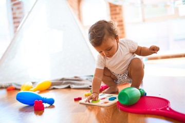 Adorable toddler learning numbers using maths puzzle around lots of toys at kindergarten