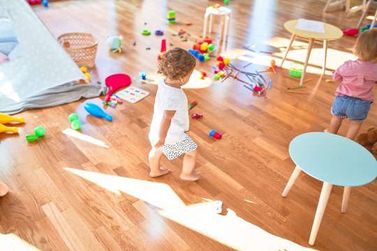 Adorable toddler playing around lots of toys at kindergarten