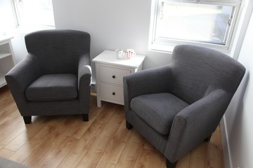 Two cozy grey armchairs standing on wooden floor in empty authentic apartment room