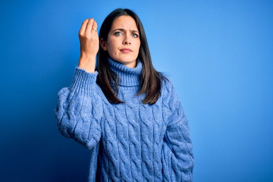Young brunette woman with blue eyes wearing casual turtleneck sweater Doing Italian gesture with hand and fingers confident expression