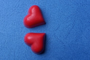 two red hearts made of sweets lie on a blue table