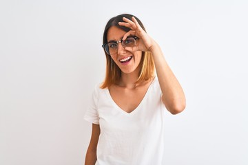 Beautiful redhead woman wearing glasses over isolated background doing ok gesture with hand smiling, eye looking through fingers with happy face.