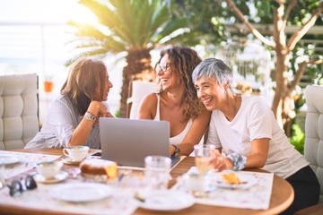 Meeting of middle age women having lunch and drinking coffee. Mature friends smiling happy using...