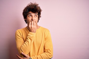 Fototapeta na wymiar Young handsome man wearing yellow casual t-shirt standing over isolated pink background looking stressed and nervous with hands on mouth biting nails. Anxiety problem.