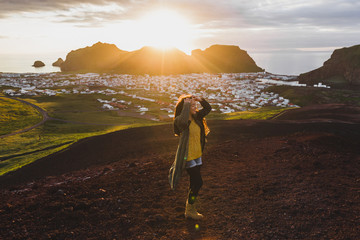 Young happy woman enjoying sunset on peak of Eldfell volcano with panoramic view of Vestmannaeyjar island in Iceland. Wanderlust travel concept. Amazing colorful sunset. © Oleg Breslavtsev