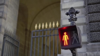 Traffic light for pedestrians, close up. Daytime. Green silhouette of a walking man, red silhouette of a standing man. Looped video. Facade of the building in the background. Ultra HD stock footage