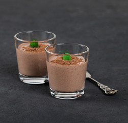 Chocolate nut jelly in a glass on a dark background.