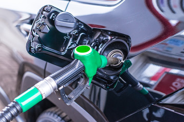 Pumping gasoline fuel in car at gas station. Petrol being pumped into a motor vehicle car. Fueling tank of the car oil pump