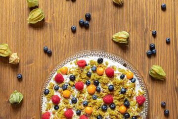 Moostorte aus grünem Biscuit mit Quark, Sahne, Früchte, Blaubeere, Himbeere, Physalis auf Holz