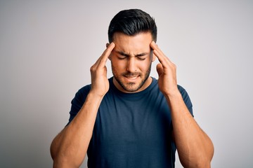 Young handsome man wearing casual t-shirt standing over isolated white background with hand on head for pain in head because stress. Suffering migraine.