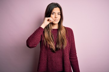Young beautiful girl wearing casual sweater over isolated pink background mouth and lips shut as...