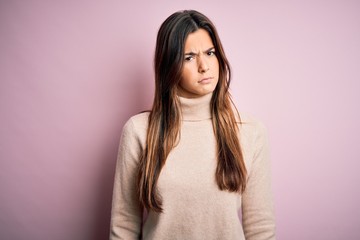 Naklejka premium Young beautiful girl wearing casual turtleneck sweater standing over isolated pink background skeptic and nervous, frowning upset because of problem. Negative person.