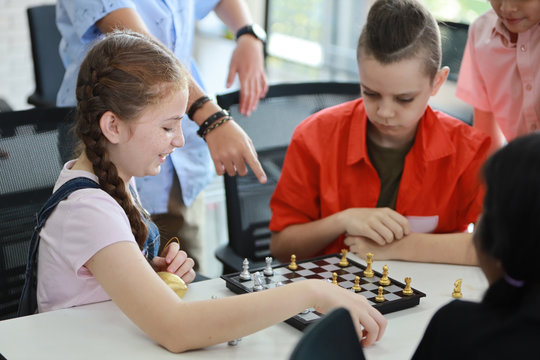 cute and smart kids sitting and playing chess in classroom (education concept)