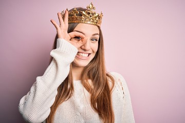 Young beautiful redhead woman wearing queen crown over isolated pink background doing ok gesture...