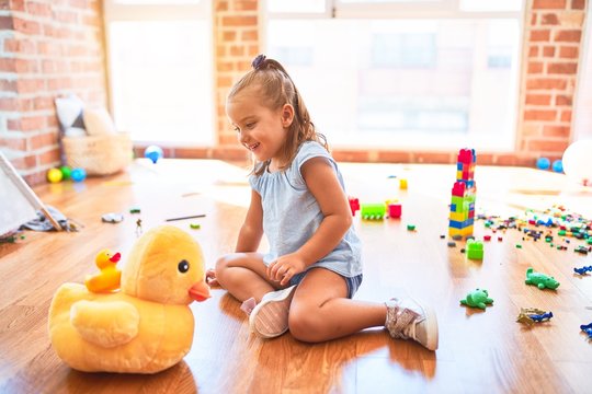 Young beautiful blonde girl kid enjoying play school with toys at kindergarten, smiling happy playing with stuffed animal at home