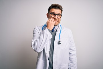 Young doctor man with blue eyes wearing medical coat and stethoscope over isolated background...