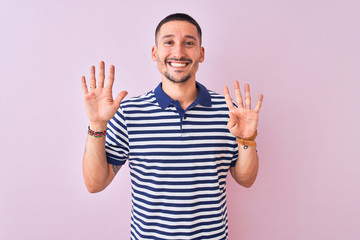 Naklejka premium Young handsome man wearing nautical striped t-shirt over pink isolated background showing and pointing up with fingers number nine while smiling confident and happy.
