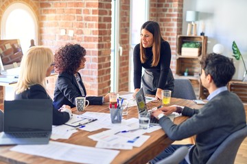 Group of business workers smiling happy and confident. Working together with smile on face. Young beautiful woman standing explaining documents at the office