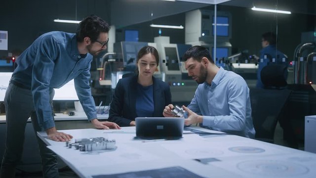Factory Office Meeting Room: Team of Engineers Gather Around Conference Table, They Discuss Project Blueprints, Inspect Mechanism, Find Solutions, Use Laptop. Industrial Technology Factory