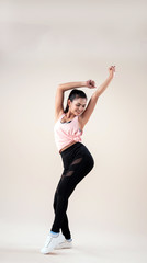 Young lady wearing exercise set twisted her body a littleraise hands up in the air,point toe down,show basic of dance workout,with happy feeling