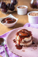 Grießflammerie aus Grieß mit Kakao und Sahne mit gekochtem Pflaumenmus und Pflaumen auf rosa ovalem Teller und Holz