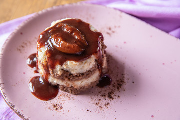 Grießflammerie aus Grieß mit Kakao und Sahne mit gekochtem Pflaumenmus und Pflaumen auf rosa ovalem Teller und Holz