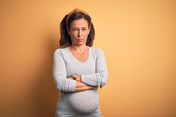 Obraz premium Middle age pregnant woman expecting baby at aged pregnancy skeptic and nervous, disapproving expression on face with crossed arms. Negative person.