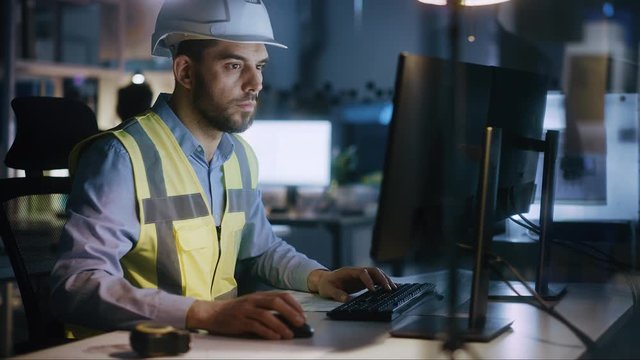 Electronics Design Factory: Portrait of Handsome Male Engineer Wearing Safety Vest Working on Computer, Developing Industrial Microchips, Semiconductor, Manufacturing Processors. Arc Shot