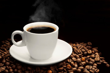 Coffee cup with hot smoke and coffee beans on dark black background