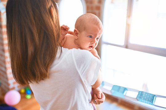 Young beautifull woman and her baby standing at home. Mother holding and hugging newborn