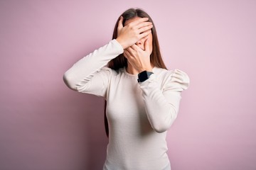 Young beautiful woman with blue eyes wearing casual white t-shirt over pink background Covering eyes and mouth with hands, surprised and shocked. Hiding emotion