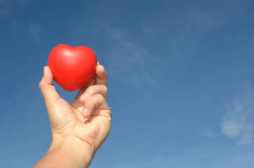 Hands holding heart, love concept with blue sky