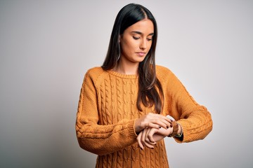 Young beautiful brunette woman wearing casual sweater over isolated white background Checking the...