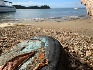 Old and dirty tire on beach. Small island is on the background.