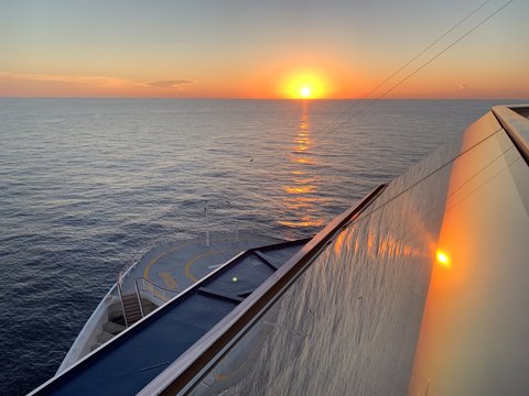 Cruise ship in the middle of the sea. Beautiful sunset with view from the bridge on a helipad.