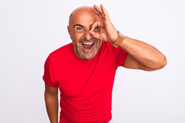 Middle age handsome man wearing red casual t-shirt standing over isolated white background doing ok gesture with hand smiling, eye looking through fingers with happy face.