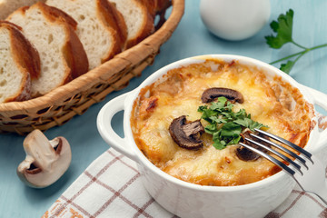 Casserole with chicken, mushrooms and cheese, known in Russia as julienne in white bowl with herbs, close up