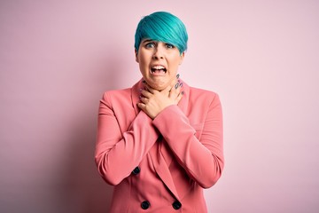 Young beautiful businesswoman with blue fashion hair wearing jacket over pink background shouting and suffocate because painful strangle. Health problem. Asphyxiate and suicide concept.