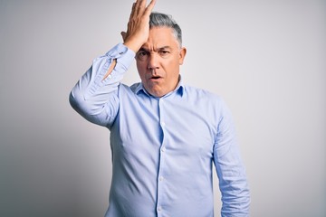 Middle age handsome grey-haired business man wearing elegant shirt over white background surprised with hand on head for mistake, remember error. Forgot, bad memory concept.